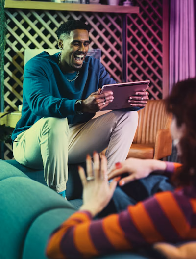 A male customer using a tablet while laughing